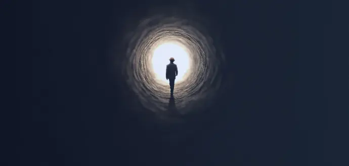 Tunnel nero con una persone diretta verso l'uscita. L'uscita è molto luminosa