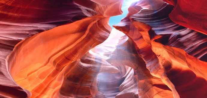 Struttura rocciosa color arancione, molto ondulata e il sole riflette sulle pareti
