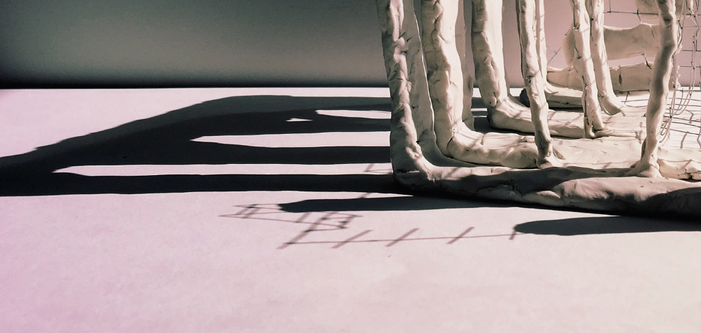 Struttura bianca con diverse sbarre. Riflette la sua ombra sul pavimento bianco