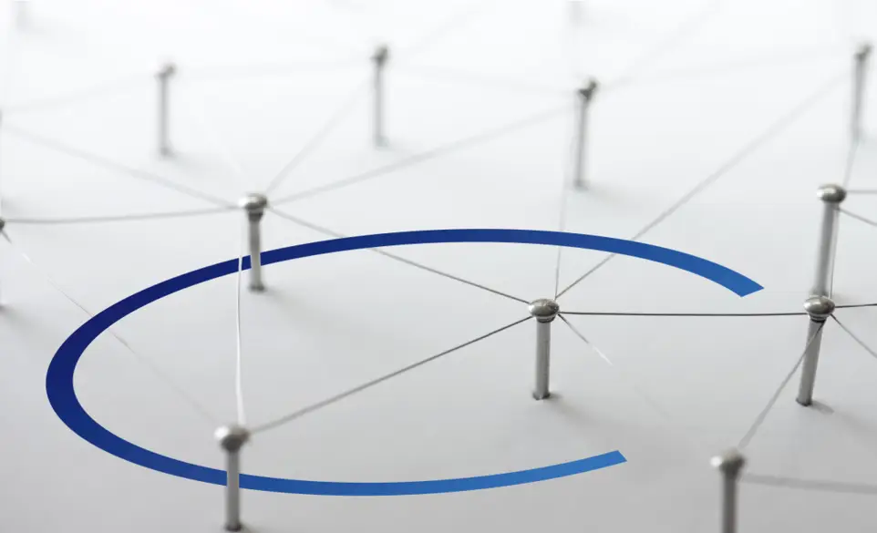 Diversi chiodi consficcati in un foglio bianco che ricorpe l'intera immagine. I chiodi sono legati tra di loro da un filo di ferro. Circonferenza blu che passa sotto i chiodi